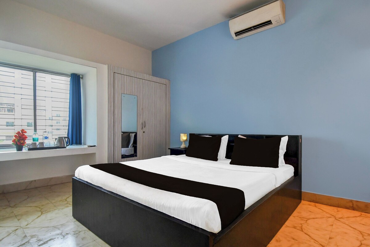 Quarto de hotel com cama, janela com cortinas, guarda-roupa e ar condicionado.