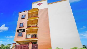 Un hotel de varios pisos con balcones, un letrero que indica que es un hotel de servicios de empresa, y una entrada porticada.