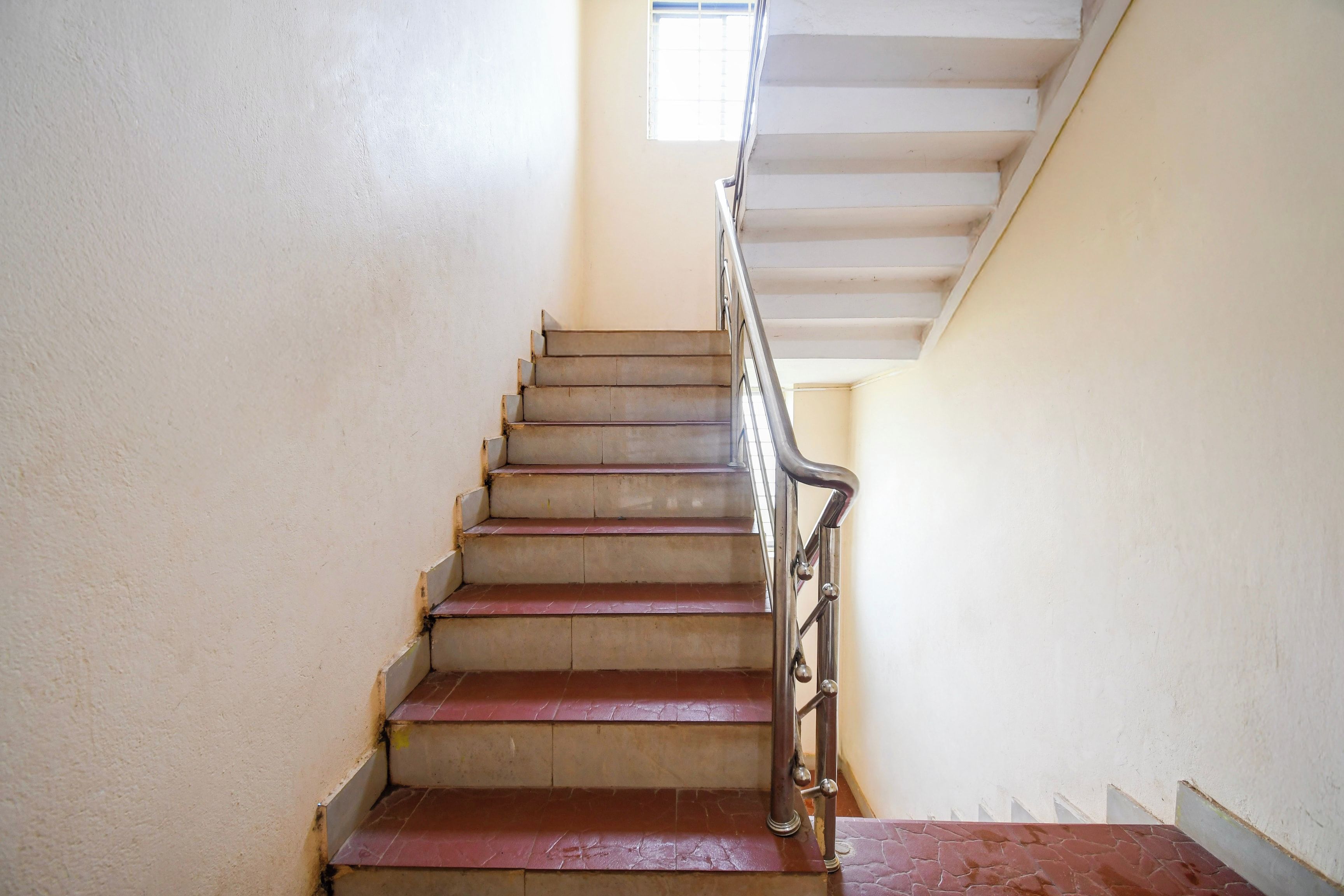 A staircase with a metal handrail and a red-tiled landing.
