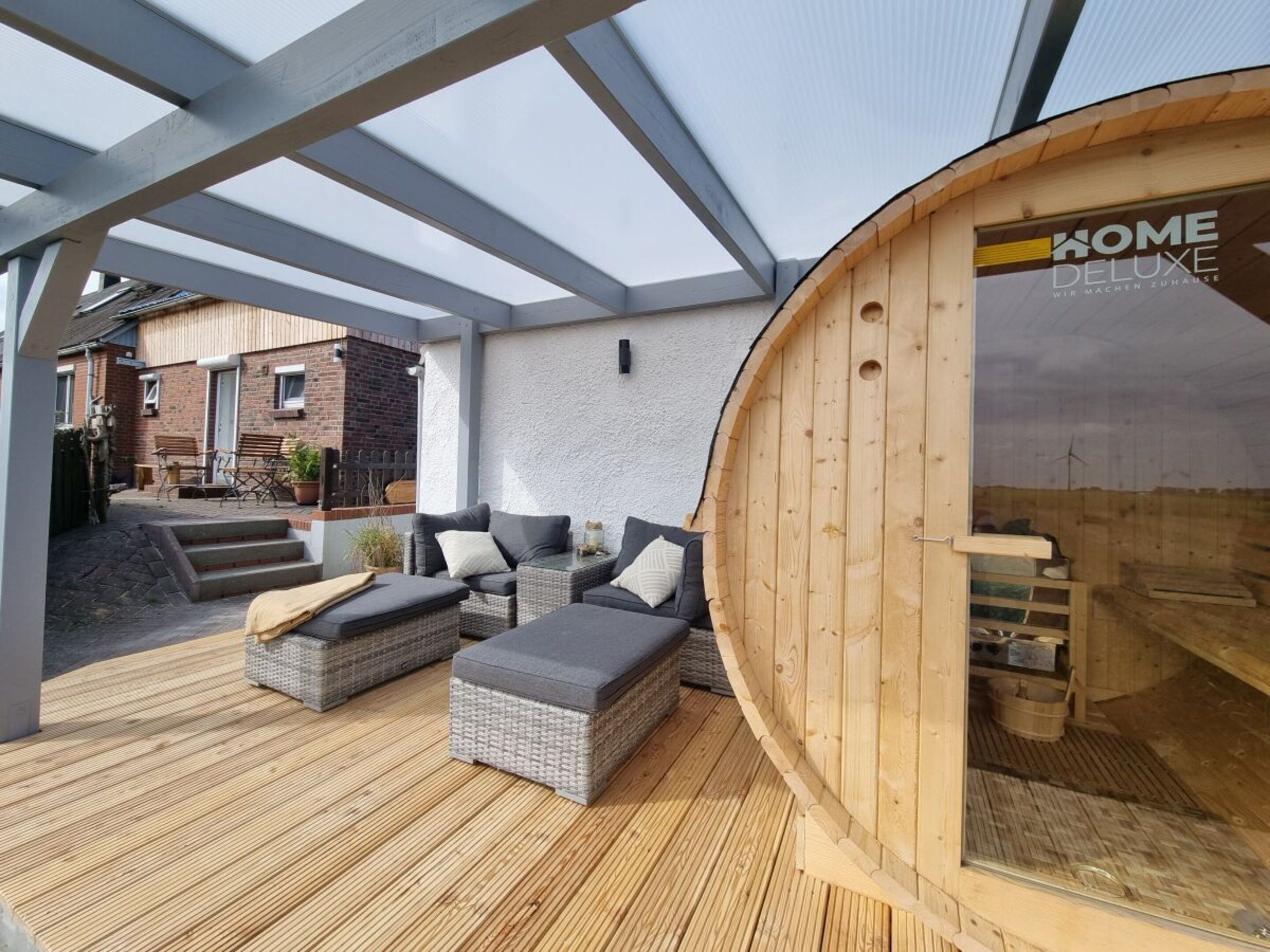 A covered outdoor seating area with wicker furniture and a wooden structure labeled 'HOME DELUXE.'