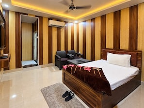 Ein Hotelzimmer mit Bett, Schreibtisch, Stuhl, kleinem Tisch und Klimaanlage.