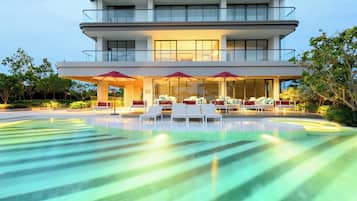A modern multi-story building with a swimming pool and outdoor seating area.