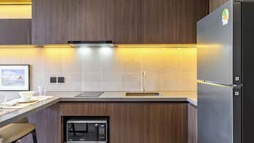 A modern kitchen with a built-in microwave, stainless steel refrigerator, and a wooden cabinet.