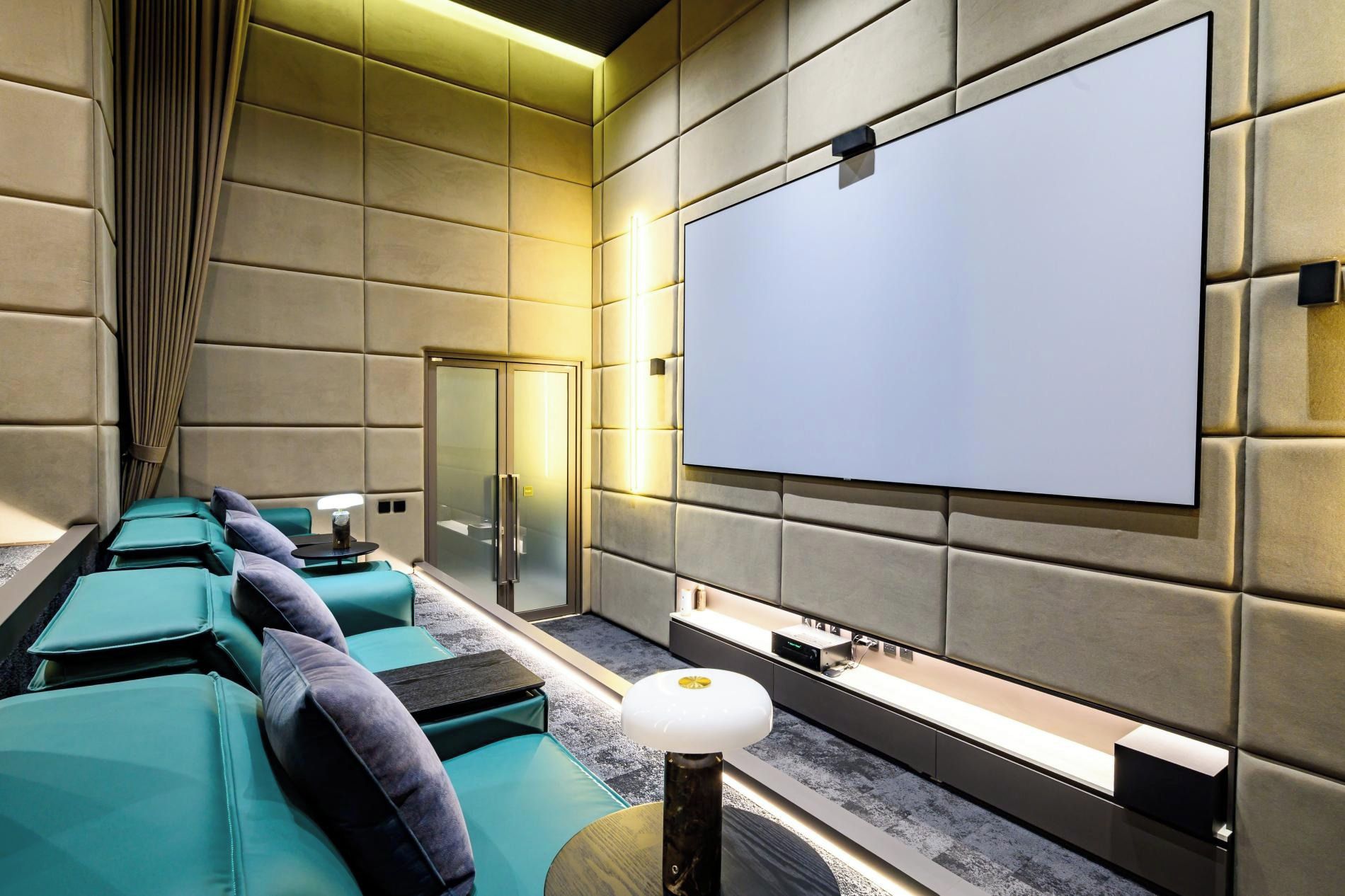 Una sala de cine moderna con asientos mullidos, una pantalla grande y un diseño elegante.