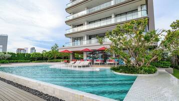 Un hotel moderno con piscina infinita en la azotea, asientos al aire libre y exuberante vegetación.