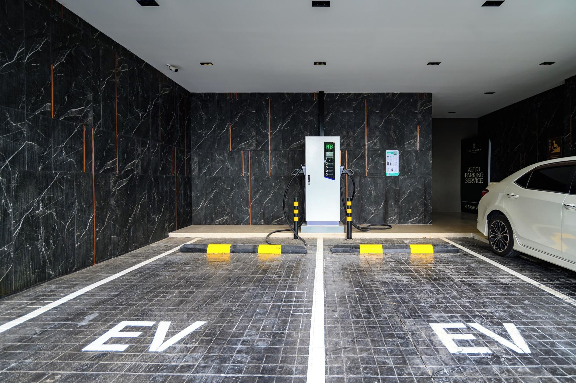 Una estación de carga para vehículos eléctricos en un edificio moderno con paredes de mármol y un coche blanco estacionado cerca.