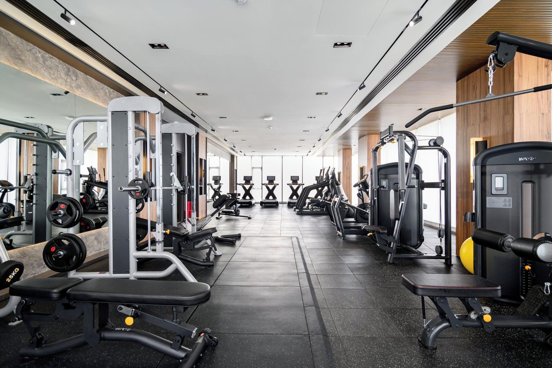 A gym with various exercise equipment, including treadmills, weight machines, and free weights.