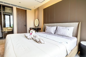Habitación de hotel con cama, mesita de noche, espejo y vista al mar.