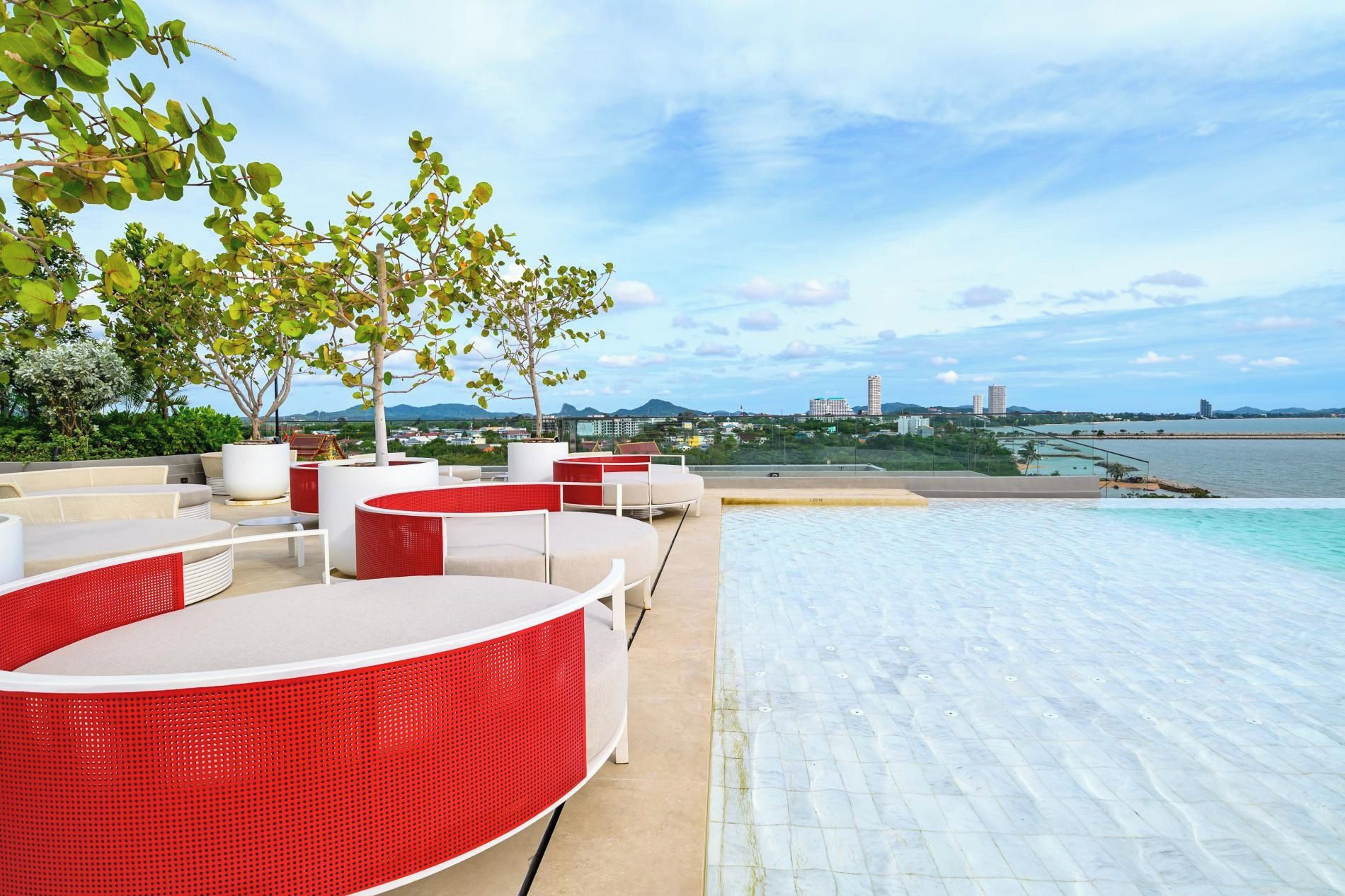 Un área de piscina en la azotea con sillones de descanso y vistas al mar.