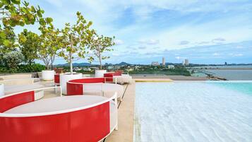 Un área de piscina en la azotea con sillones de descanso y vistas al mar.