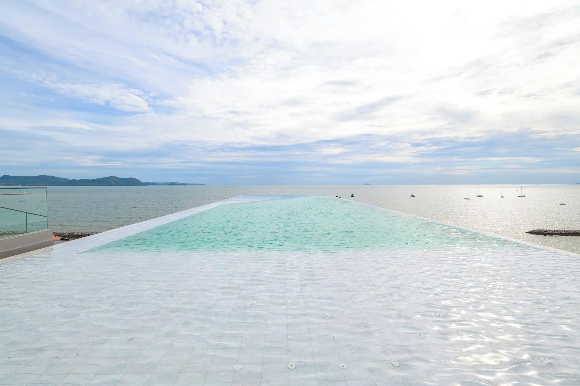 A rooftop infinity pool with a view of the sea and distant mountains.