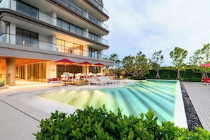 Un edificio moderno con piscina, mobiliario exterior y un jardín cuidado.