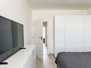 Ein Schlafzimmer mit einem Bett, einem Fernseher auf einer weißen Kommode und einem Kleiderschrank.
