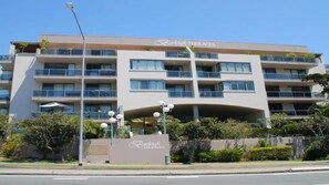 Ein mehrstöckiges Hotel mit Balkonen, einem Schild mit der Aufschrift 'Burleigh TERRACES' und einem angelegten Eingangsbereich.