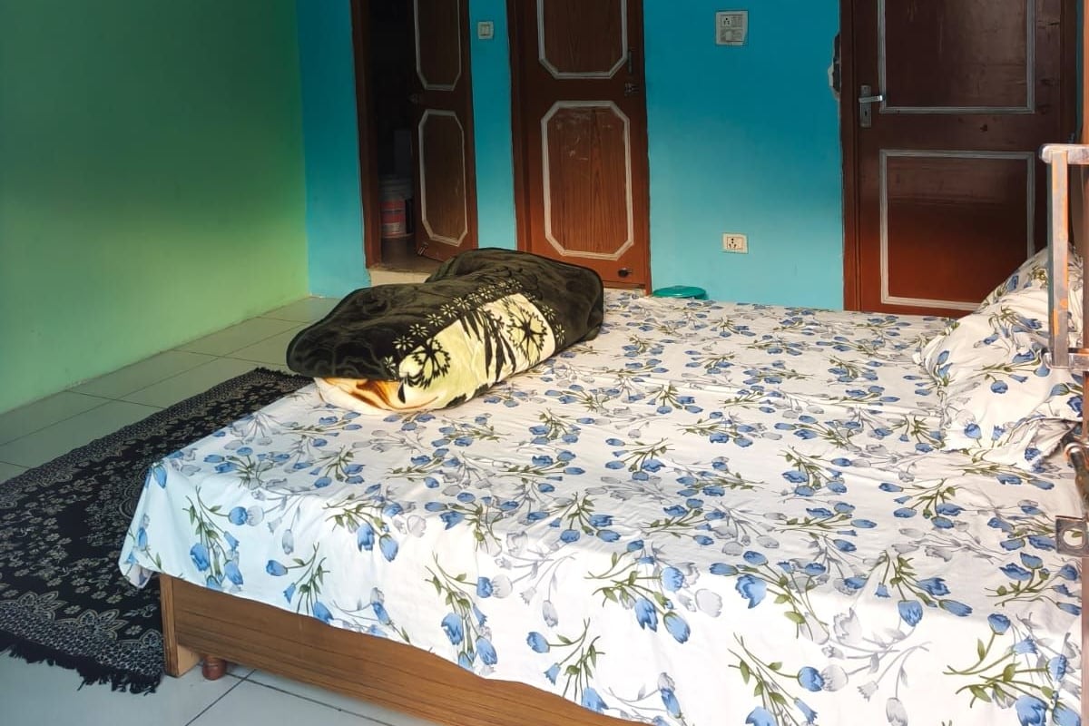 A bedroom with a bed, two doors, a light fixture, and a tiled floor.