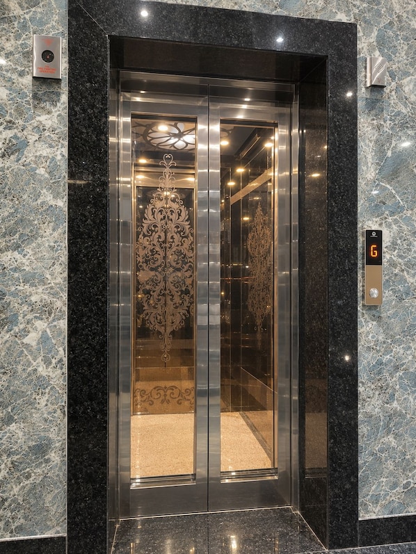 An elevator with a digital display showing the number 6, surrounded by marble walls.
