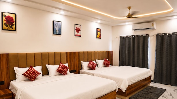 Habitación de hotel con dos camas, ventilador de techo, unidad de aire acondicionado y obras de arte en las paredes.