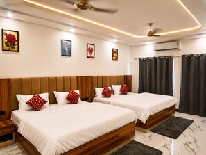 A hotel room with two beds, a ceiling fan, an air conditioning unit, and artwork on the walls.
