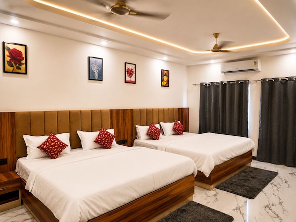 A hotel room with two beds, a ceiling fan, an air conditioning unit, and artwork on the walls.