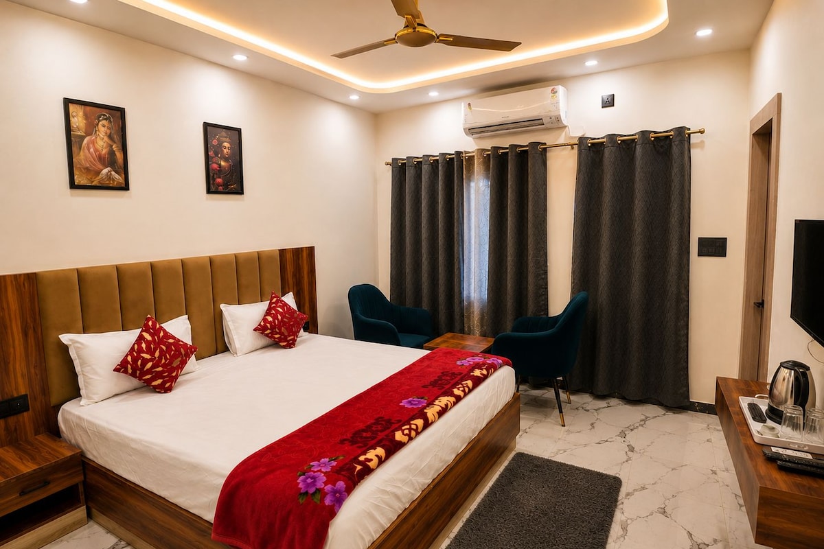 A hotel room with a bed, a desk with a coffee maker, a TV, and a ceiling fan.