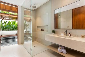 Ein modernes Badezimmer mit Duschkabine aus Glas, einem großen Spiegel und einem integriertem Waschbecken.