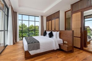 A modern hotel room with a large bed, wooden headboard, and a view of greenery through large windows. - Blanc Haven Canggu by Kerta Living (Badung)