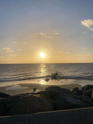 Ein Strand mit Felsen im Vordergrund und dem Meer im Hintergrund.