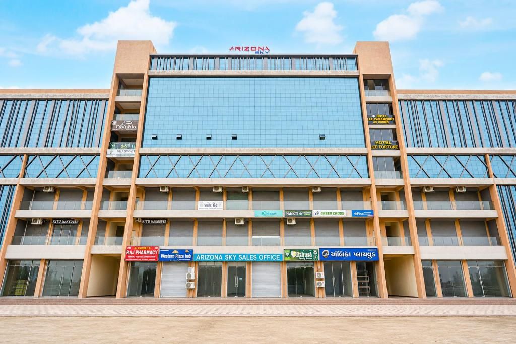 Un edificio de varios pisos con fachada de vidrio moderna, que cuenta con un letrero llamativo para 'Arizona Sky Sales Office' en la planta baja.