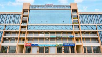 Un edificio de varios pisos con fachada de vidrio moderna, que cuenta con un letrero llamativo para 'Arizona Sky Sales Office' en la planta baja.