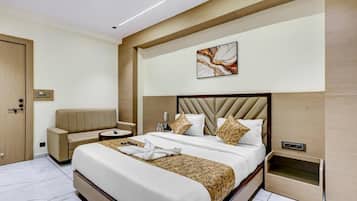 A hotel room with a large bed, a sofa, a bedside table, and a wall-mounted artwork.