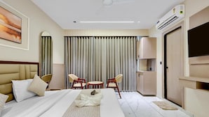 Una habitación de hotel con una cama grande, un escritorio, dos sillas, un televisor y un equipo de aire acondicionado.