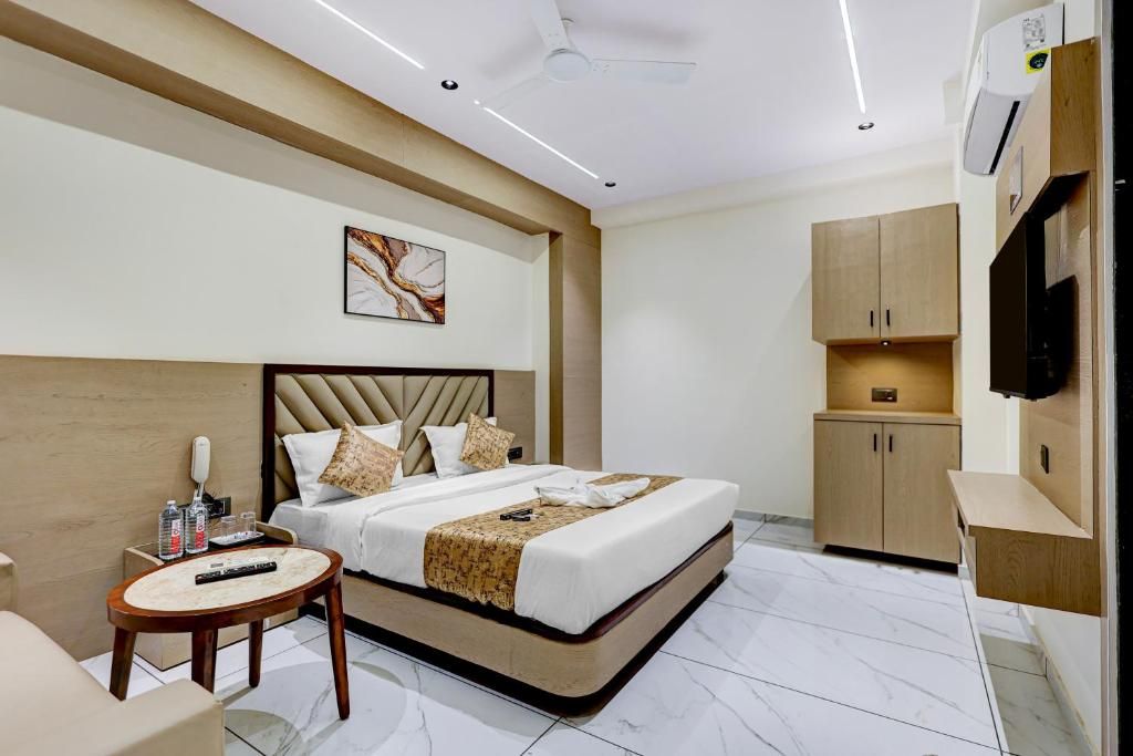 A modern hotel room with a bed, bedside table, and a TV mounted on the wall.
