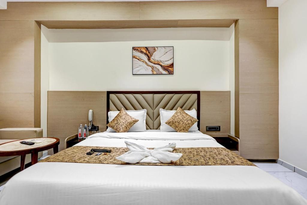 Een hotelkamer met een groot bed, een nachtkastje, een stoel en een kunstwerk aan de muur.