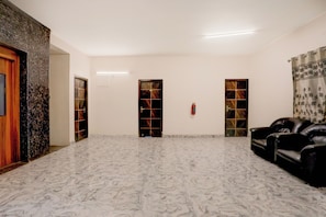 A spacious room with a marble floor, a black leather sofa, and two doors with decorative glass panels. - Townhouse Oak Tirupati Formerly Sky (Tirupati)