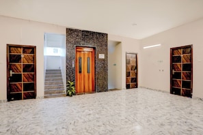 A hallway with marble flooring, wooden doors with glass panels, and a staircase leading to an upper floor. - Townhouse Oak Tirupati Formerly Sky (Tirupati)