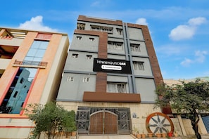 A multi-story building with a sign indicating 'TOWNHOUSE OAK' and 'Company-Served' amenities. - Townhouse Oak Tirupati Formerly Sky (Tirupati)