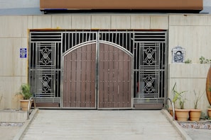 A gated entrance with a large metal gate, potted plants, and a decorative emblem on the wall.