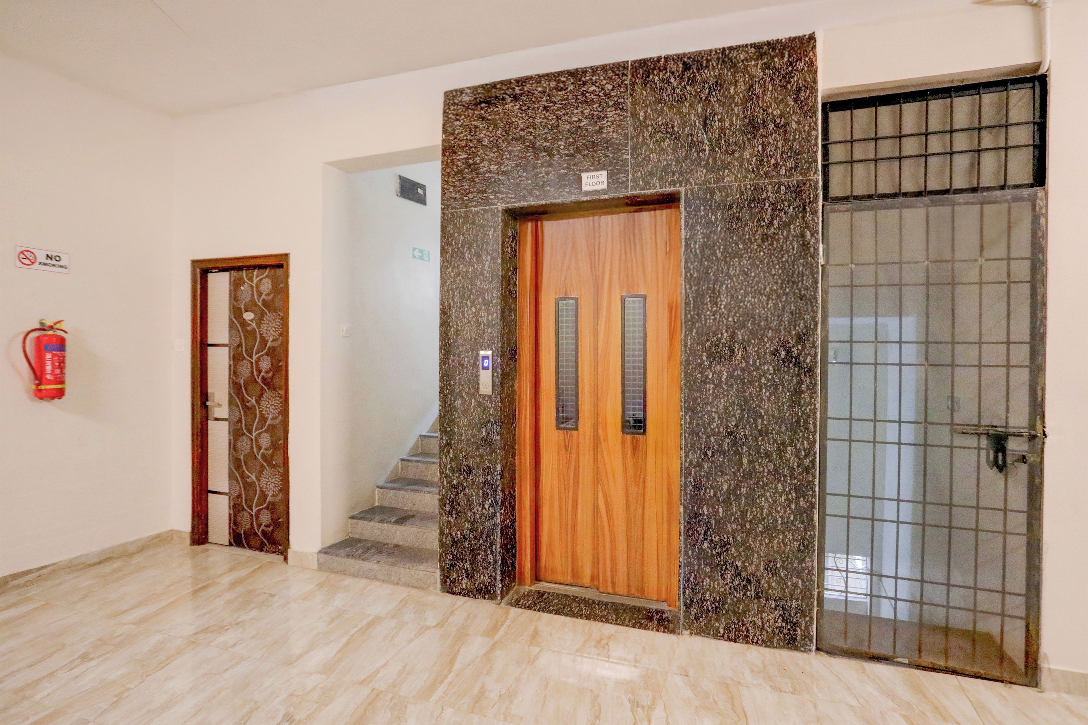 A hotel lobby with a wooden door, a fire extinguisher, and a tiled wall.