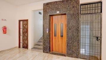 Un vestíbulo de hotel con una puerta de madera, un extintor y un muro con azulejos.