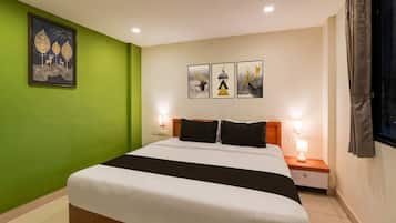 A hotel room with a bed, green walls, and artwork on the wall.