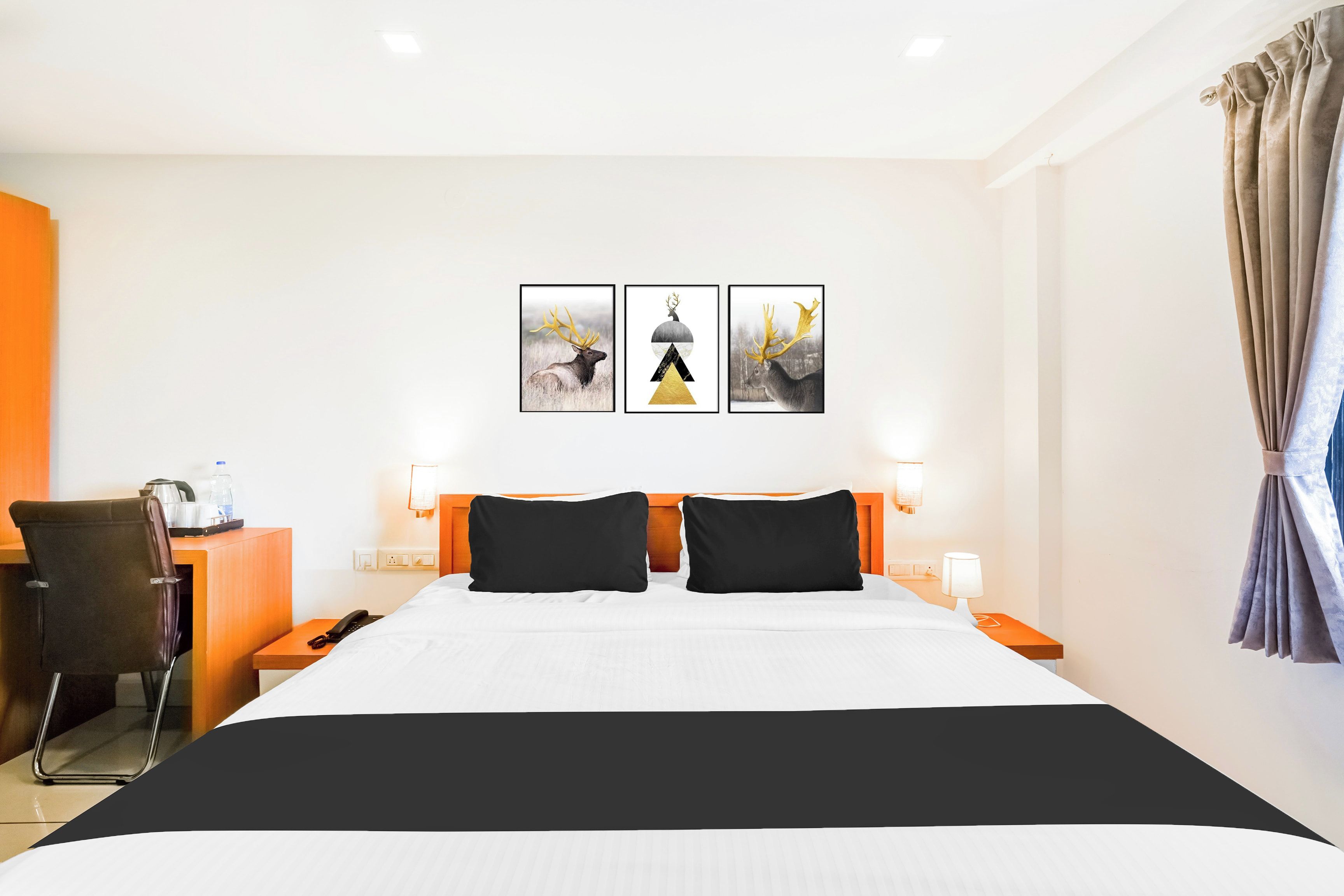 A hotel room with a bed, a desk, a chair, and artwork on the wall.