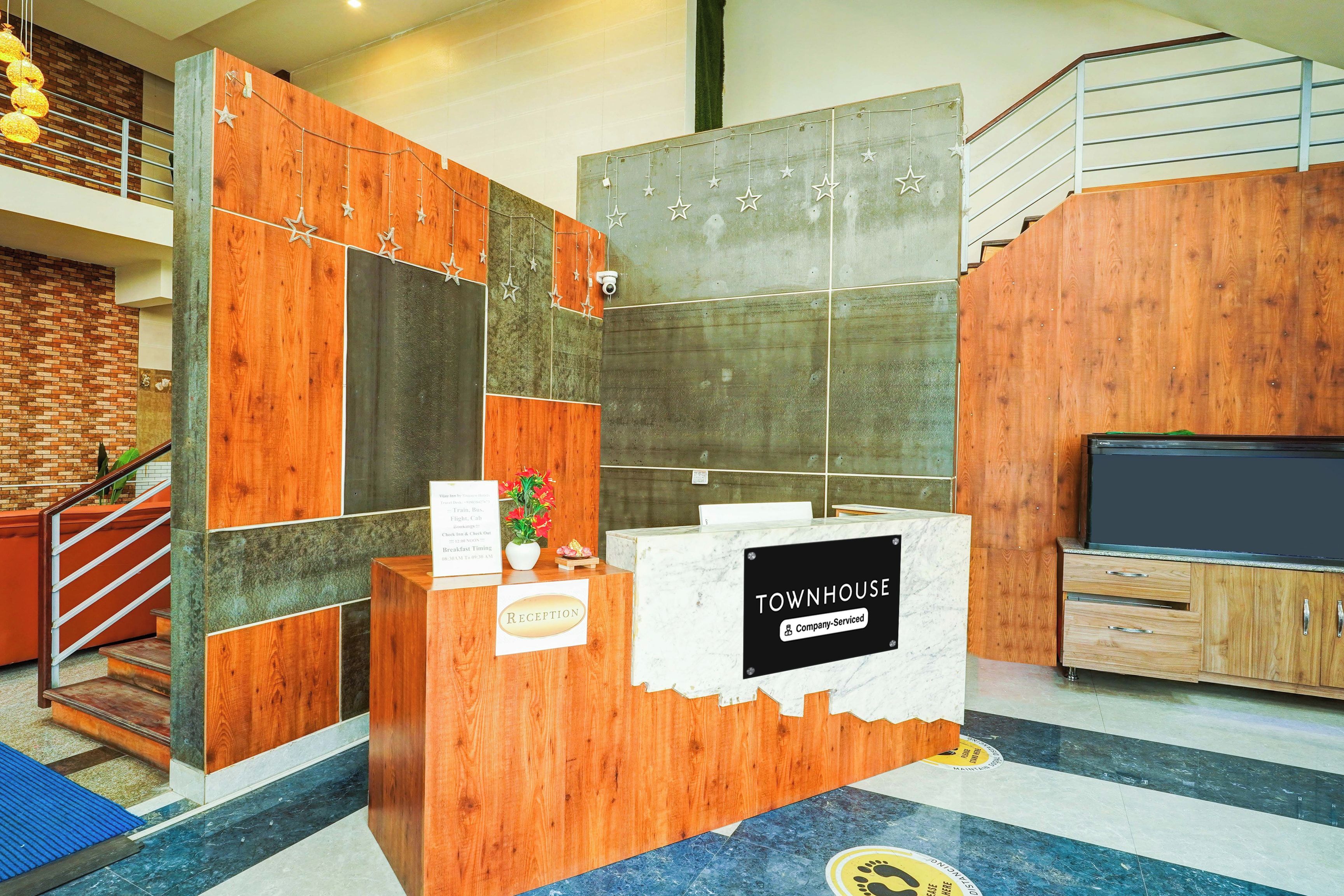 A reception desk with a sign reading 'TOWNHOUSE Company-Serviced' and a small plant on it.