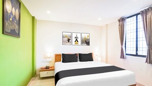 Een hotelkamer met een groot bed, een nachtkastje en een raam met gordijnen.