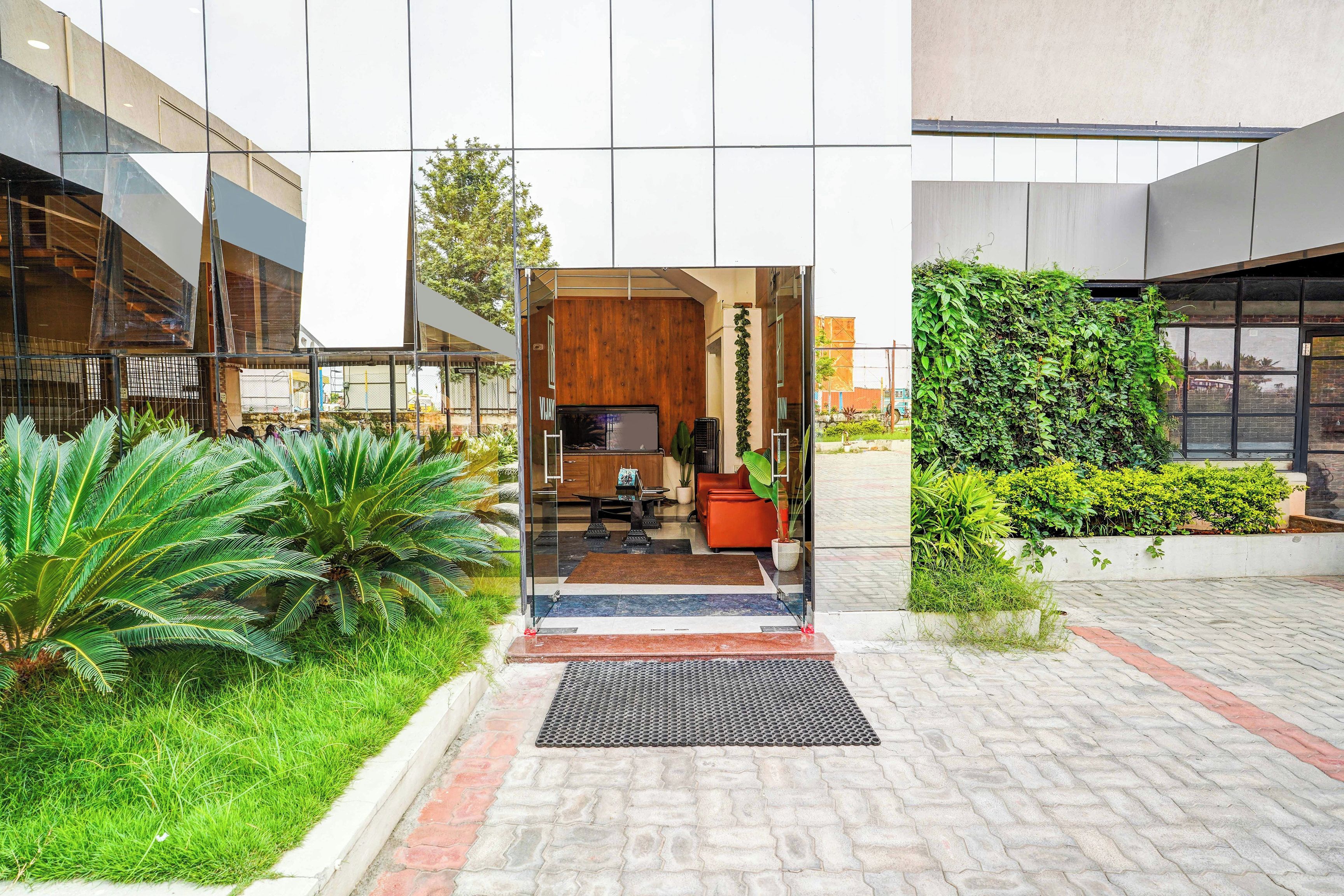 A modern building entrance with a reception desk, seating area, and a view of the surrounding greenery.