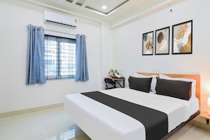 A hotel room with a large bed, a desk with a chair, a window with curtains, and wall art. - Townhouse Kokapet Formerly Aarian Tej (Hyderabad)