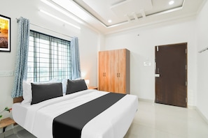 A hotel room with a bed, a wardrobe, a door, and a window with curtains. - Townhouse Kokapet Formerly Aarian Tej (Hyderabad)
