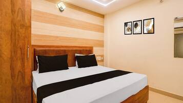 Une chambre d’hôtel avec une tête de lit en bois, un lit avec une literie blanche et noire, et trois œuvres d’art encadrées accrochées au mur.
