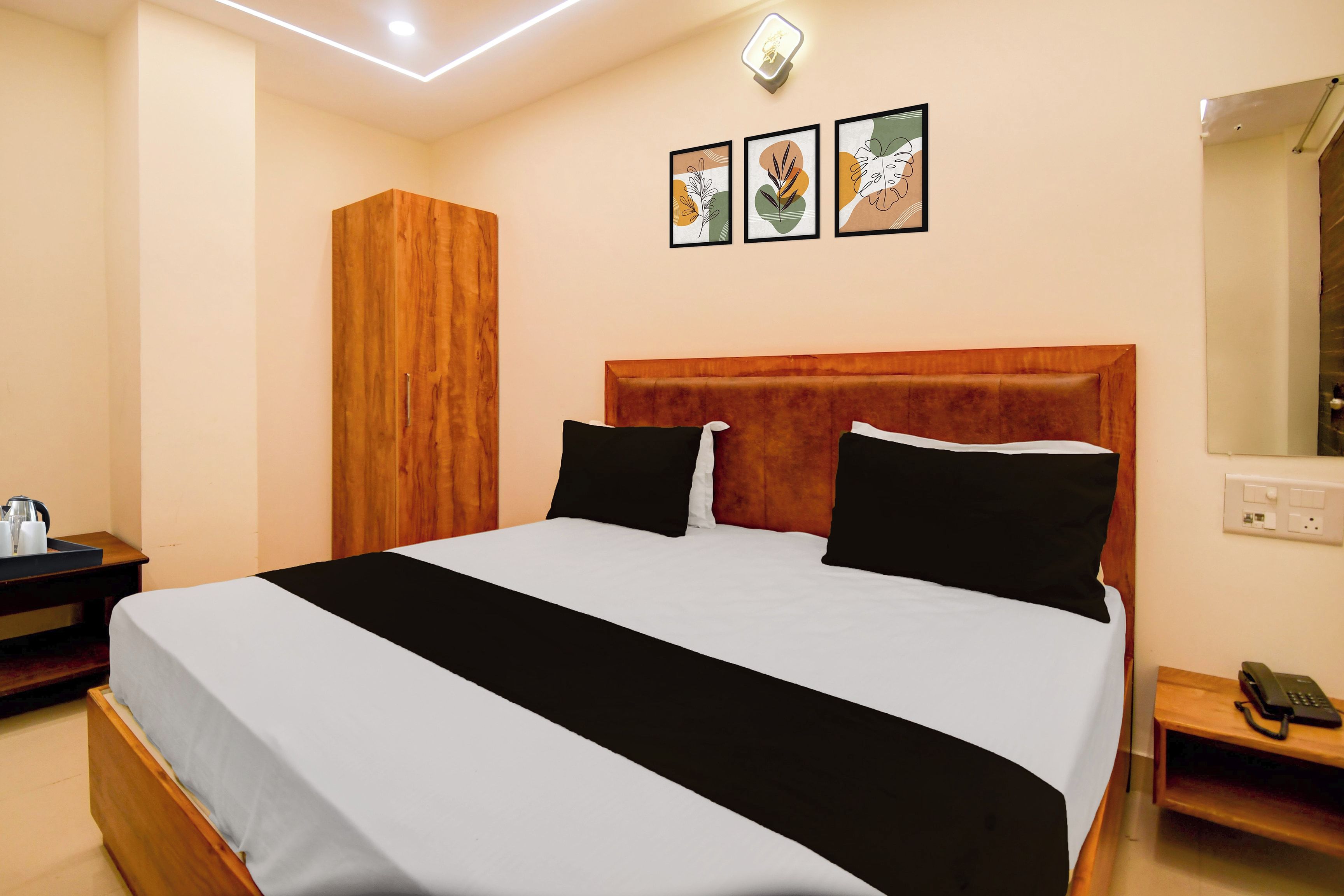 Habitación de hotel con una cama grande, un armario de madera, una mesita de noche con teléfono y una lámpara de pared.
