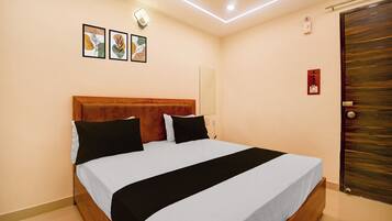 Habitación de hotel con cabecera de madera, cama con ropa de cama blanca y negra, y puerta con cerradura de botón.