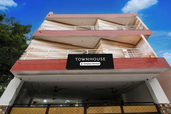 Un edificio de varios pisos con un letrero que dice 'TOWNHOUSE' y una etiqueta 'Company-Serviced'.